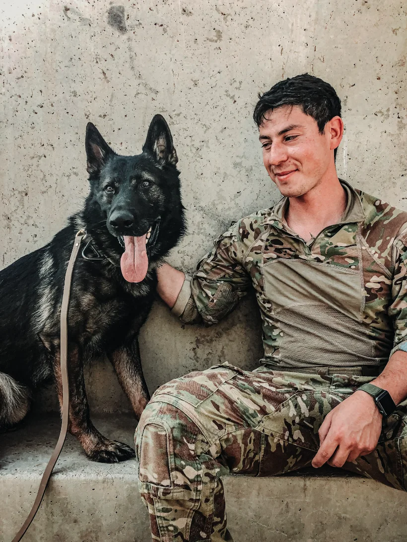 Jake Rafalson in uniform, seated beside a military working dog